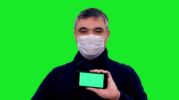 Close up of Asian Man in Protective Mask Holding Smartphone with Green Screen