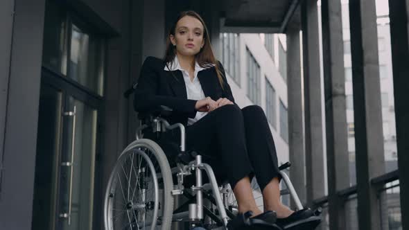 Portrait of Handicapped Beautiful Woman Ceo Executive in Suit Sitting in Wheelchair at Top of Office alt