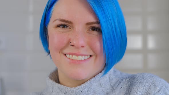 Cheerful Caucasian female with blue colored hair posing for 4k stock video clip at home alt
