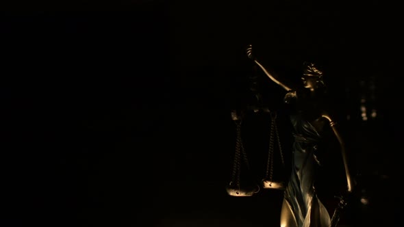 Figure of Lady of Justice illuminated with the light of a candles ...