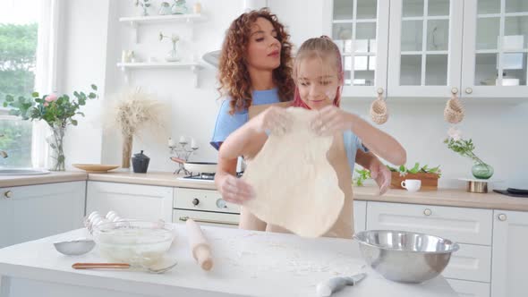 Mother and Her Teen Daughter Preparing Dough for Pizza or Cookies Together in Kitchen
