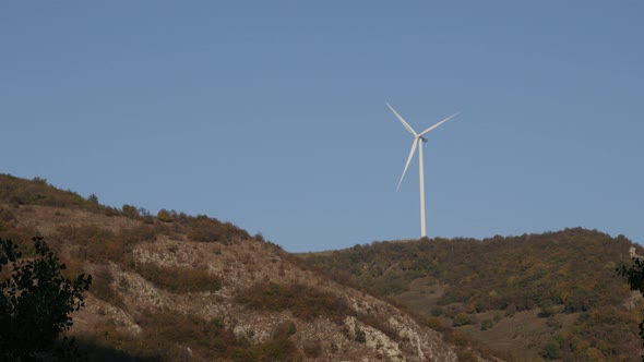 Wind turbine on top of the hill and against blue sky 4K video