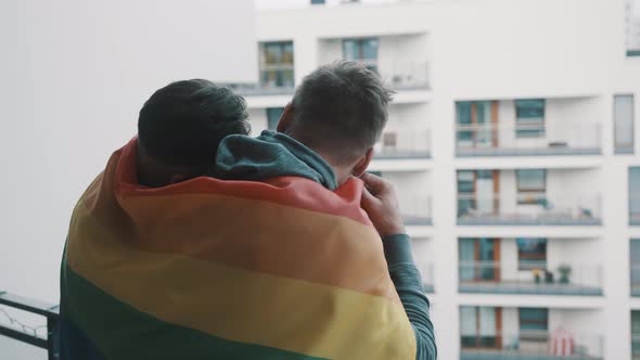 Young Homosexual Couple Enjoying the View From the Balcony Covered with Pride Rainbow Flag alt