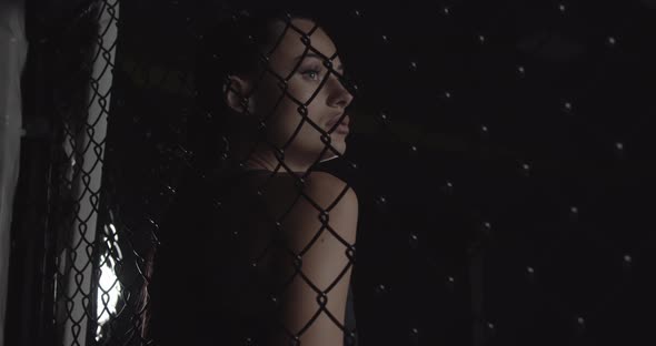 Modern Fashionable Woman Behind a Tatami Net in the Dark with a Lighted Face Looking at the Camera alt