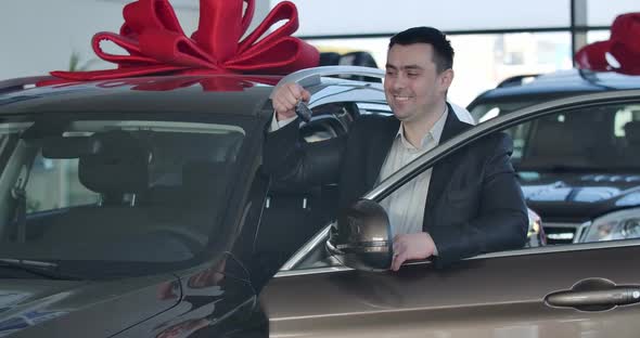 Portrait of Young Caucasian Man Standing at New Car and Bragging Keys. Happy Brunette Businessman alt