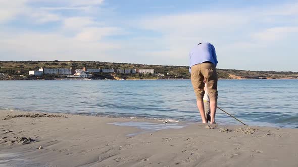 LONG SHOT of father playing with his son on the beach, holiday, near the shore line carrying a net alt