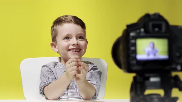 Kid blogger filming video on camera working with the laptop, at home. Online learning. Online school alt