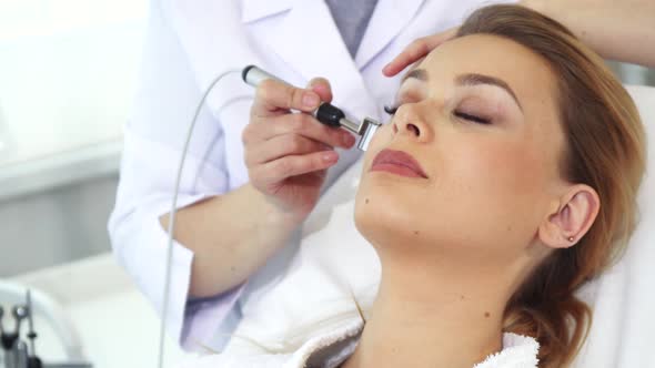 Beautician Uses Iontophoresis Roller for Client's Face