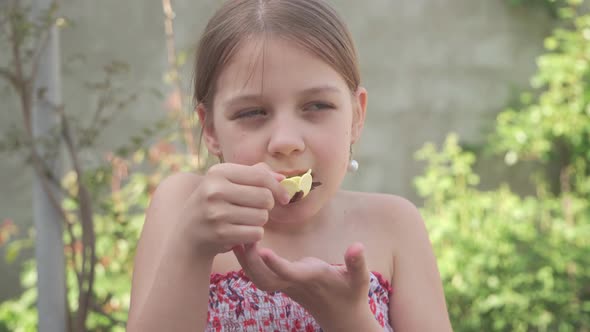 A Young Girl is Happy to Eat a Sweet Candy in the Form of a Flower