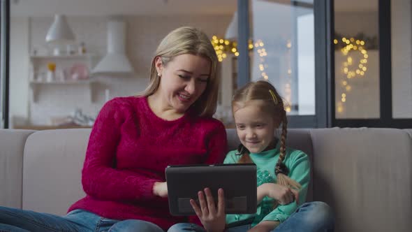 Mother and Girl on Sofa Networking with Tablet Pc alt