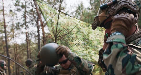 Soldiers in Military Uniform Put on Tactical Helmets in a Temporary Forest Base alt