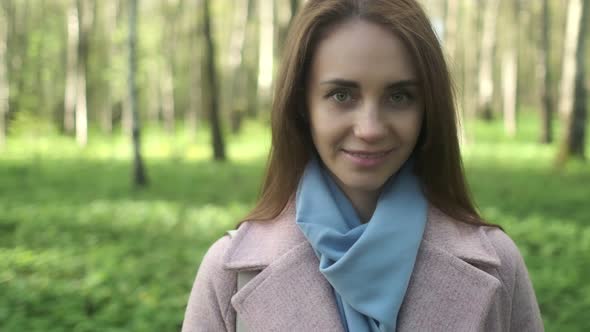 Close-up portrait of smiling woman standing in park garden outdoors. A flirtatious cute pretty girl alt