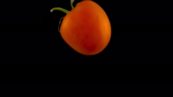 Tomato Falls in the Water in . Isolated on Black Background with Alpha. Close Up View alt
