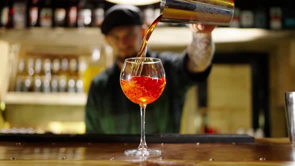 A Professional Bartender is Preparing an Alcoholic Cocktail with Ice Cubes to Customers at the Bar alt