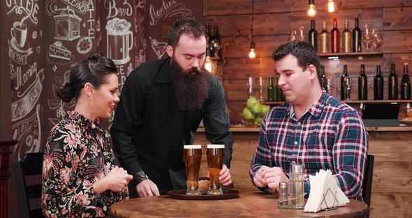 Bartender Bringing Beer To Lovely Couple in the Pub alt
