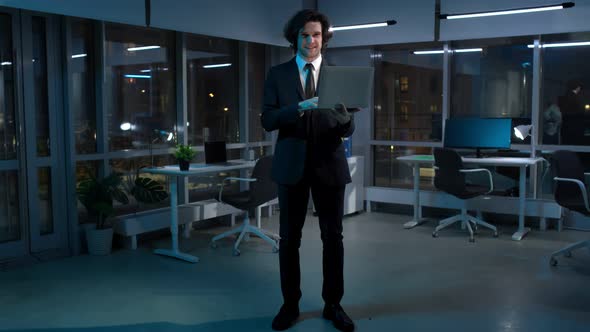 Full Length View of Handsome Entrepreneur Stand in Office with Laptop Looking at Camera alt