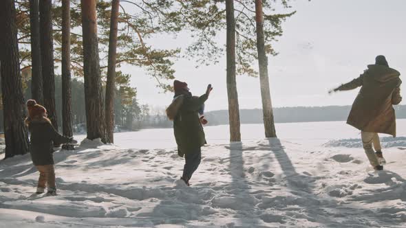 Family Throwing Snowballs on Sunny Winter Day alt