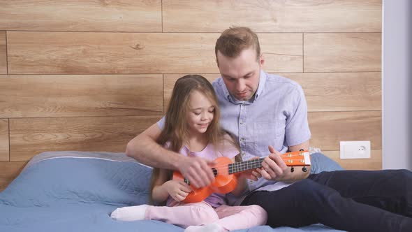 Concentrated Little Caucasian Girl Playing Ukulele Father Teaching Her