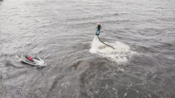 A Man Flying on the Flyboard and Other Man Riding Jet Ski in Circles  Aerial View alt