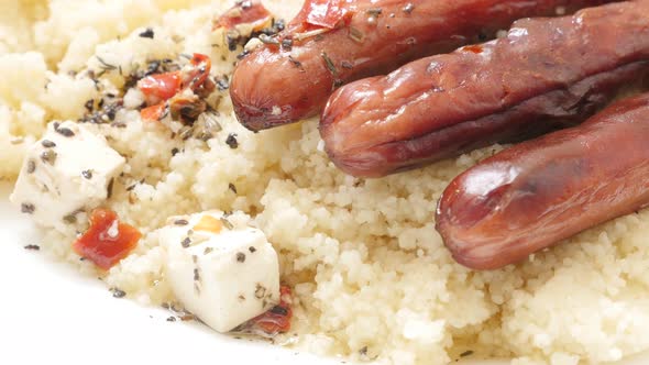 Tasty sausages cheese and couscous served on the plate slow tilt close-up 4K 3840X2160 30fps UHD vid alt