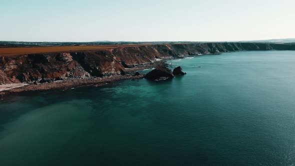 Rocks off the ocean coast line with turquoise water and dramatic cliffs Aerial view.