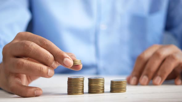 Young Man Stacking Coins on Table alt