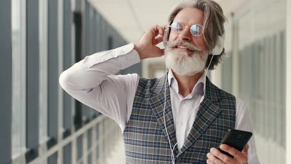 Hipster Businessman in Earphones Listening To Music with Smartphone alt