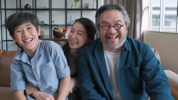 portrait of happy Asian family spending time together on sofa in living room.