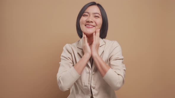 Happy asian business woman feel shy standing isolated over beige background. 4K video