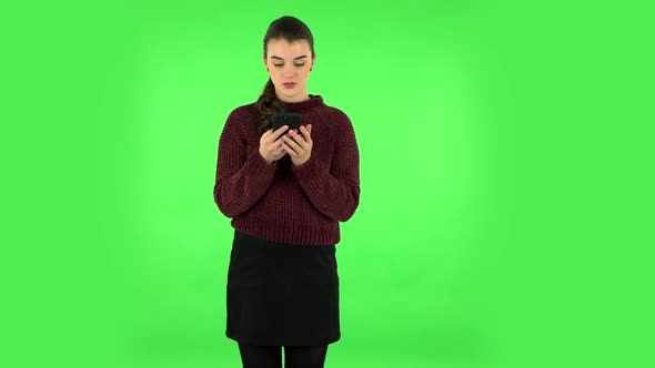 Young Smiling Woman Texting on Her Phone. Green Screen alt