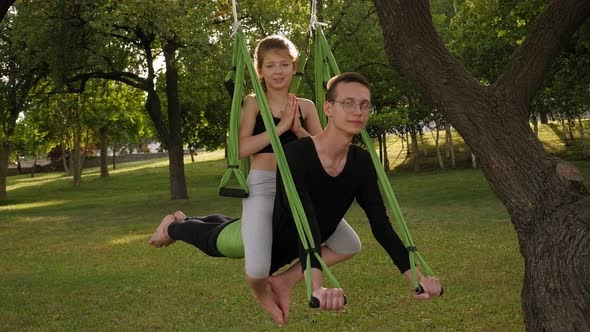 A Coach and a Child Practice Anti-gravity Yoga in a City Park. Slow Motion alt