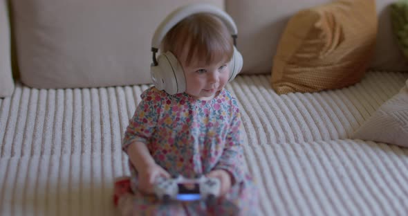 Cute Little Girl Sits with Headphones on Her Head Listens to Sounds Smiles alt