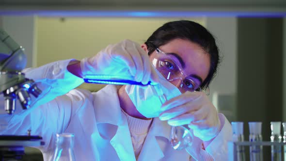 Scientist in Laboratory Doing Chemical Experiment with Blue Liquid in Test Tubes alt