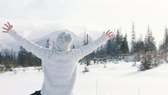 Young Woman Waching the Snowfall and Rising Her Hands on the Mountain alt