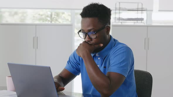 Close Up of Afroamerican Pensive Employee Working on Laptop in Office alt