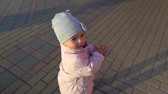 Close Up of Baby Girl Clapping Outdoor. Slow Mo. Golden Hour Time. Cute Face with Serious Expression