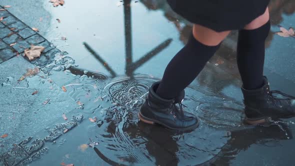 Woman Having Fun Splasing Water at Rainy Wet Weather. Female Feet Walking on City Street Pool or alt