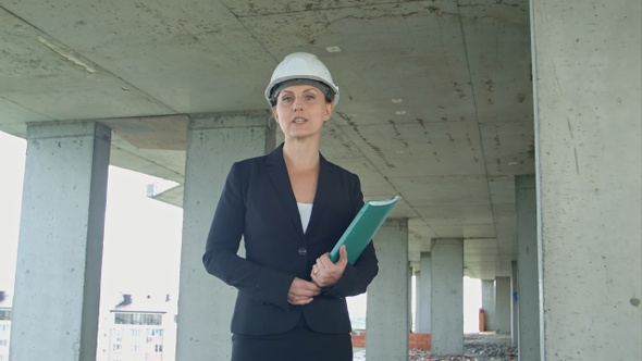 Female construction manager with blueprint on building