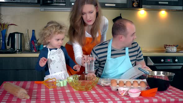 Happy Mother, Father and Cute Daughter Making Cookie Together in Kitchen