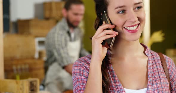 Woman talking on mobile phone at bakery section alt