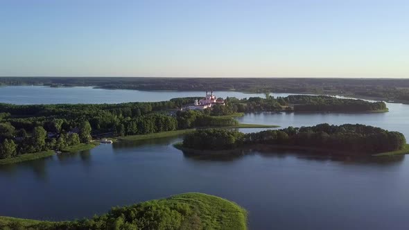 aerial shot over many small lakes and closing in to a church in the distance alt