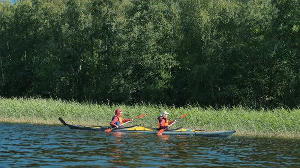 Active Rest, Two Woman Rowing Synchronously on Kayak on Lake Against Background of Forest and alt