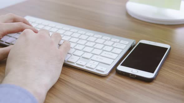 Top View of a Young Man Working with Mobile Phone Computer Keyboard and Mouse alt