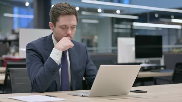 Businessman Thinking While Working on Laptop in Office alt