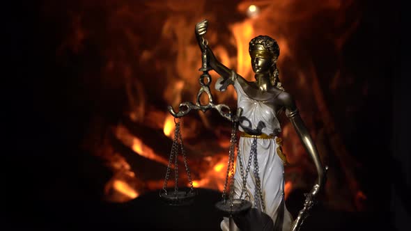 statuette of Themis on the background of the flame