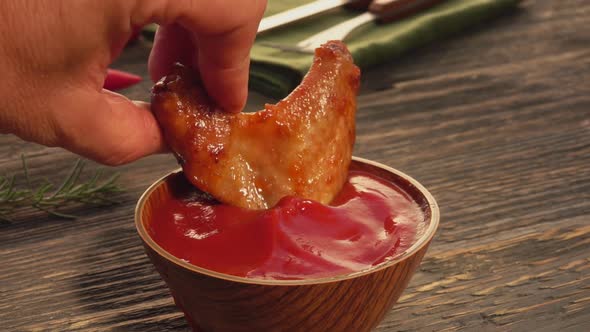 Close-up of a Male Hand Dipping a Chicken Wing Into the Ketchup alt