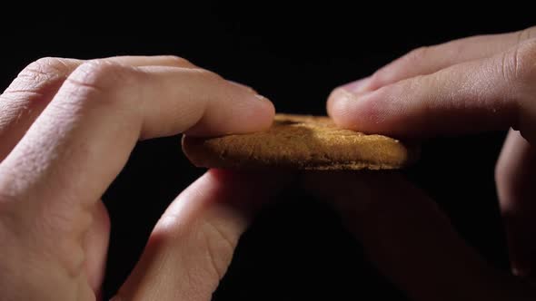 Men's Fingers Hold a Cookie and Then Break It in Half alt