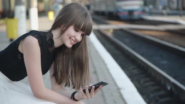 Happy Young Girl Speaking on Mobile Phone on Railway Platform alt