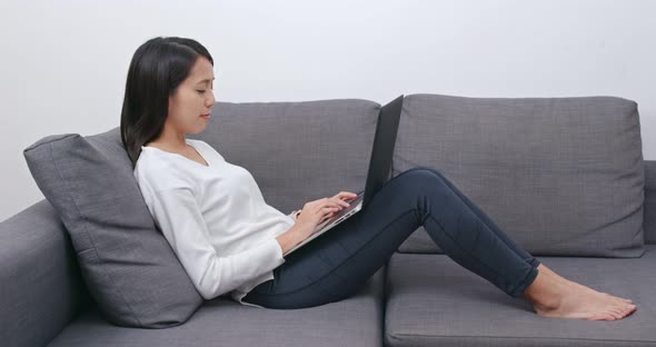 Woman work on computer and lying on sofa alt