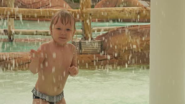 Cute Little Blond Girl is Playing and Jumping in the Small Pool in the Aquapark alt